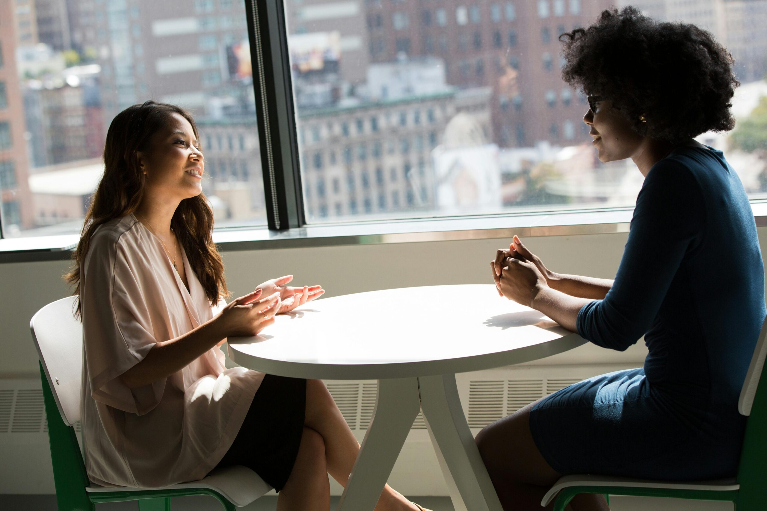Two women talking over a small table by the window